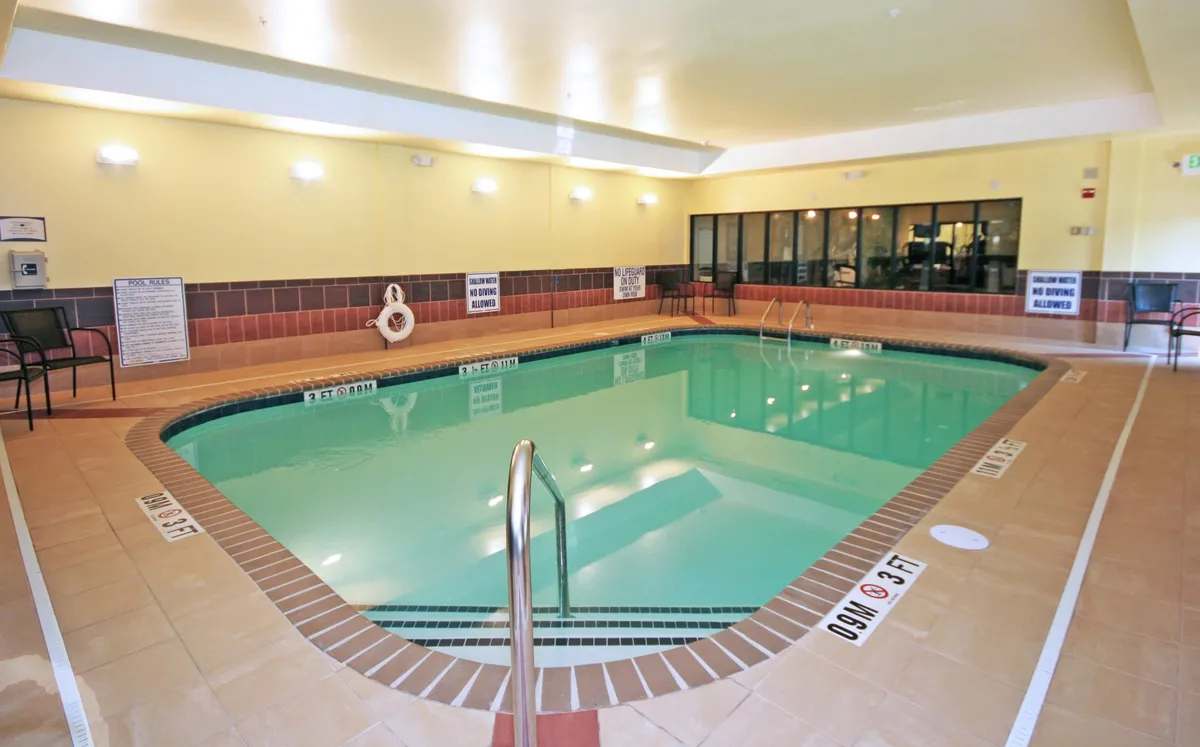 This image shows a relaxing indoor swimming pool area, complete with a ladder for easy access and a comfortable seating area for lounging. The pool area is inviting, with soft lighting and enough space for both swimming and casual socializing. The scene suggests a tranquil spot to unwind after a busy day of beach activities or exploring local attractions.