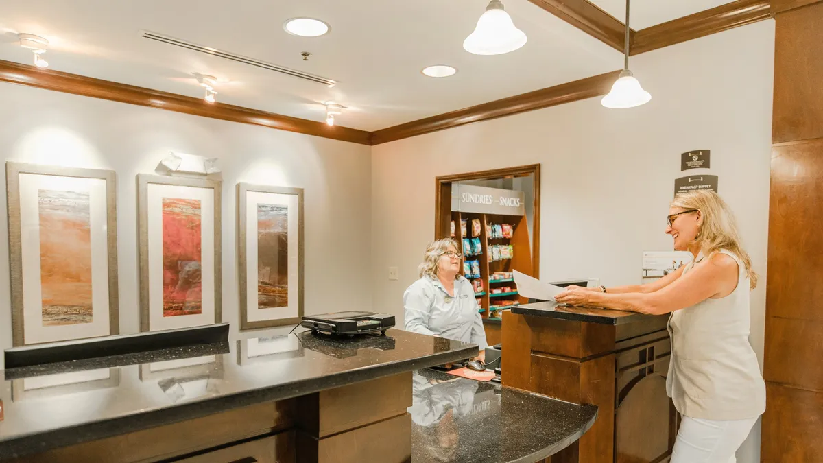 The image shows an interior area focused on a welcoming reception desk, with snacks and light refreshments visible nearby. There’s a casual, inviting atmosphere, suitable for grabbing essentials or quick bites, echoing the convenience that comes with a fully equipped kitchen.